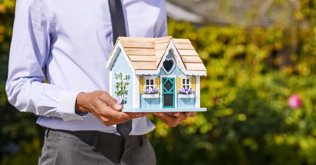 Professionnel de l'immobilier tenant une maquette de maison